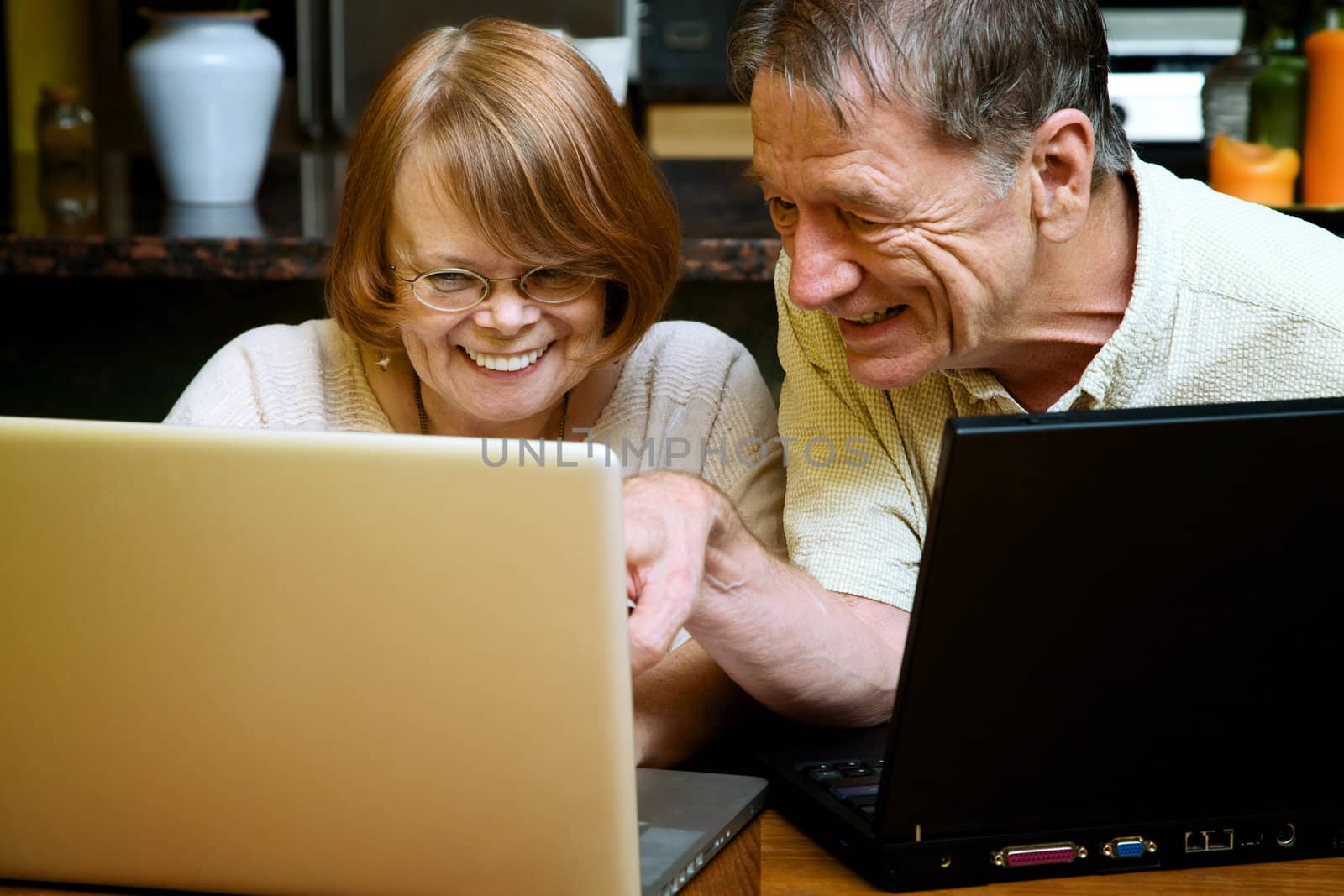 Senior couple using two laptop computers at home