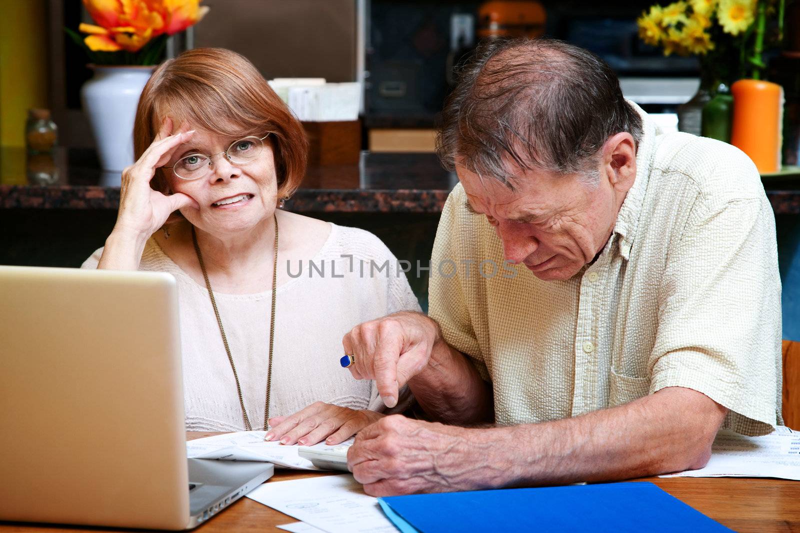 Senior couple at home reacting to many bills