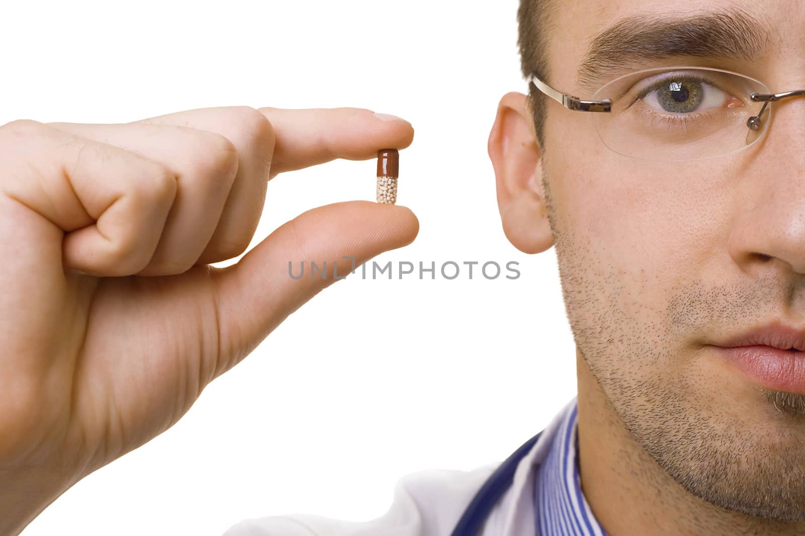 young male doctor holding pill in fingers