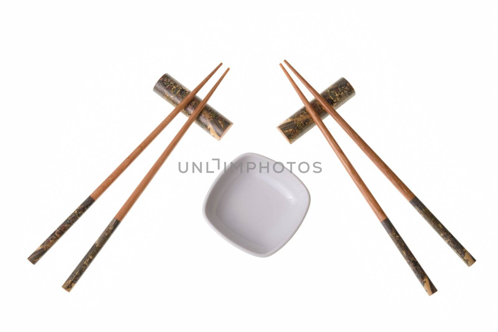 Two pairs of wooden chopsticks and white empty saucer. Sticks are decorated with temple theme ornamentation. Isolated on white