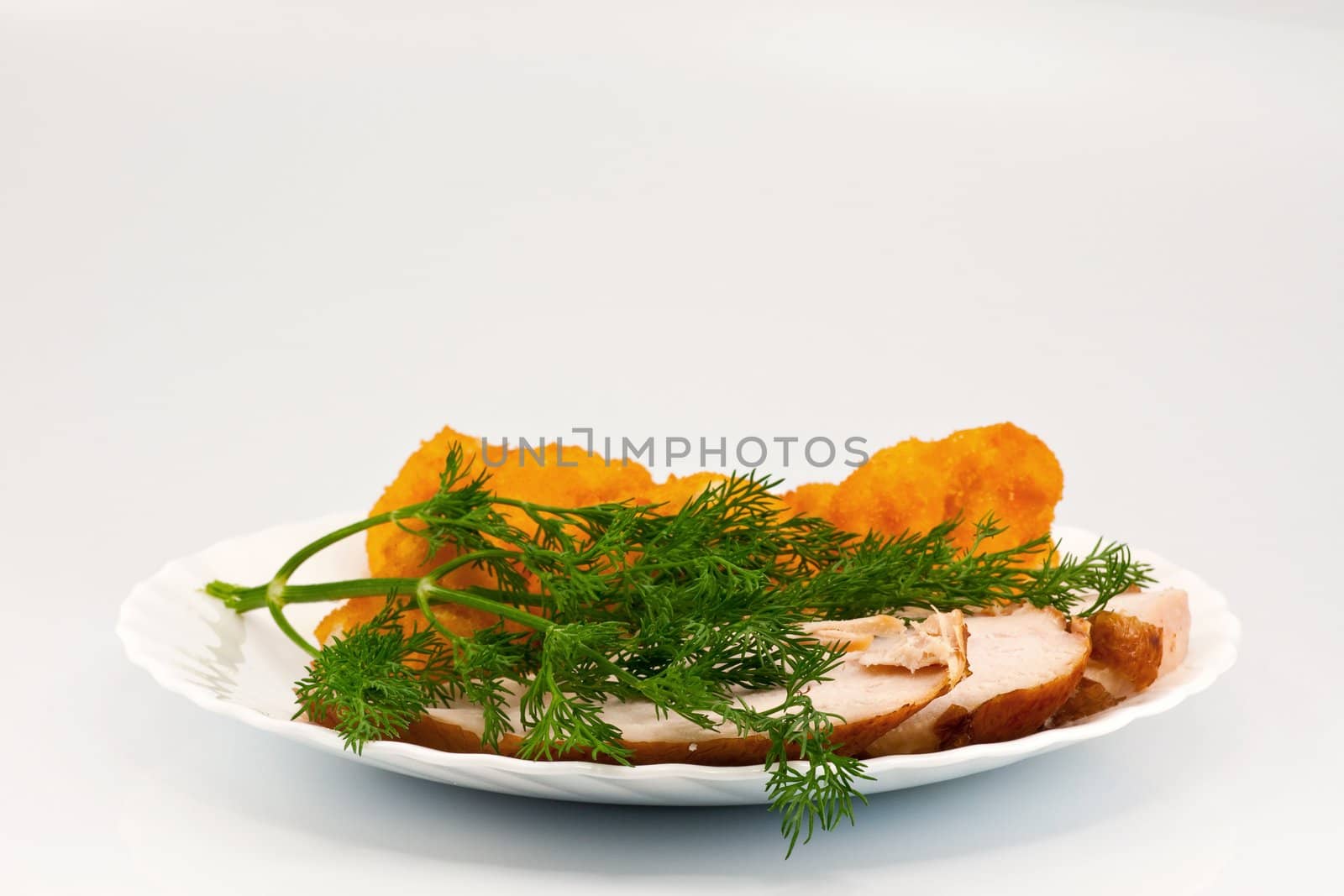 Rosted cauliflower with hot smoked chiken meat and fresh dill on white porcelain plate