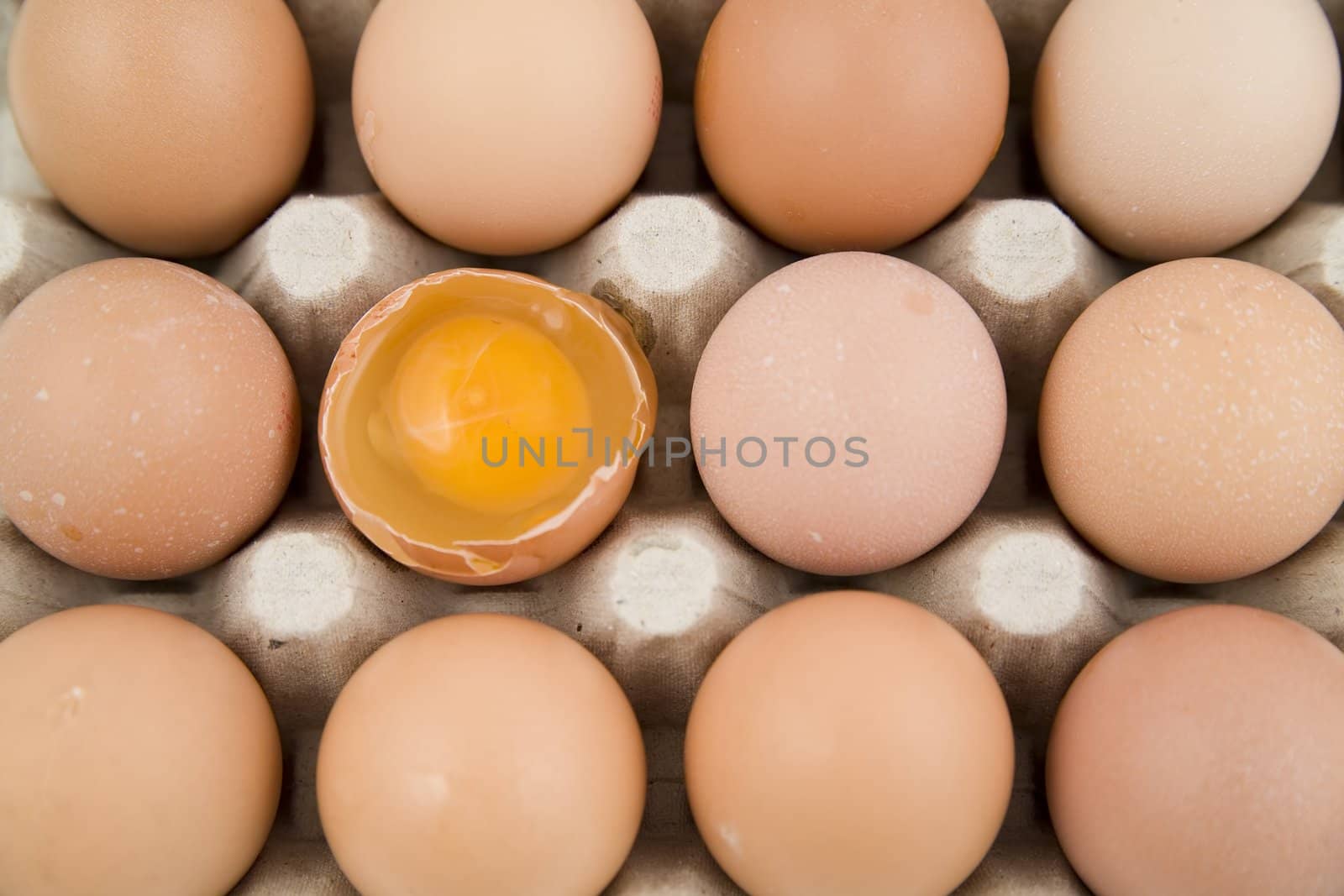 plenty of eggs in paper container. One egg is opened