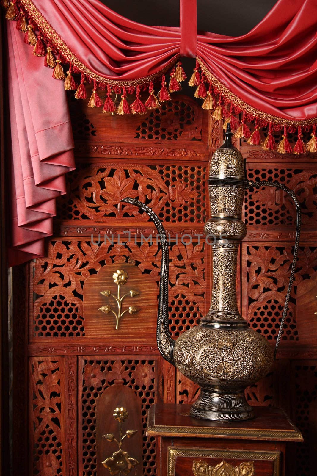 Beautiful copper an amphora against a wooden carved screen
