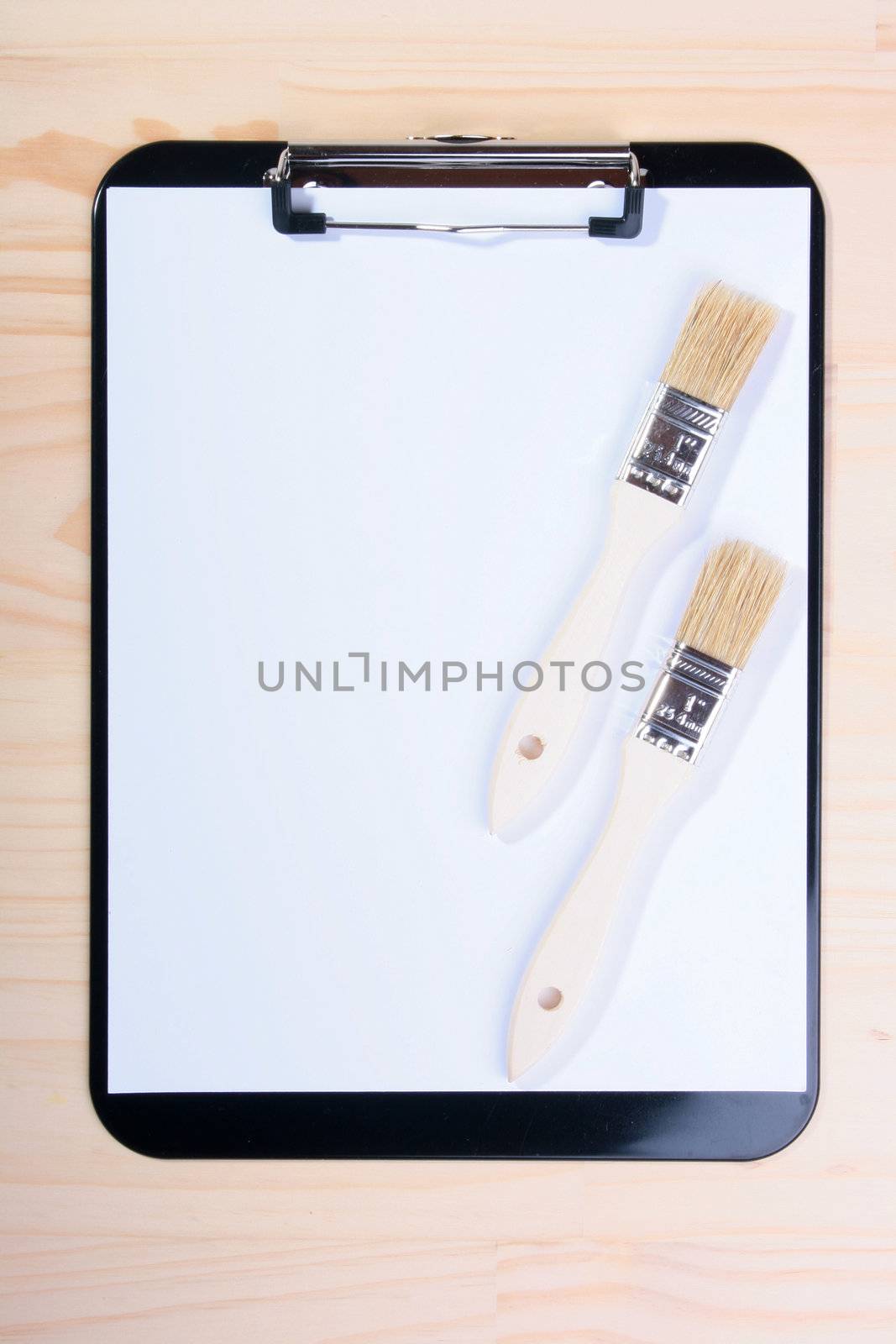 Two brushes are located on blank clipboard. The photo is intended for business connected with painting and dressing.