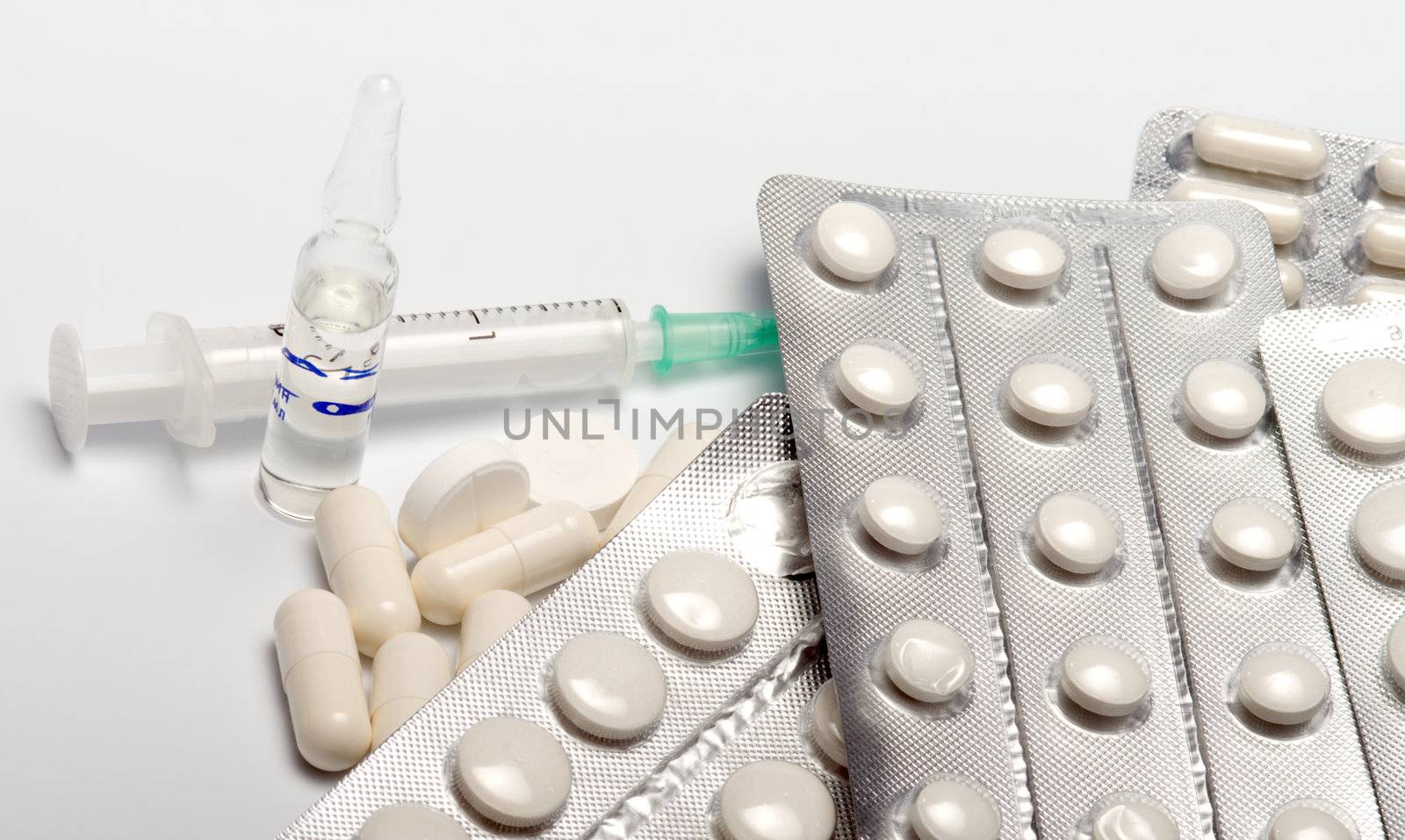 Tablets in packings of a capsule a syringe and an ampoule on a white background.