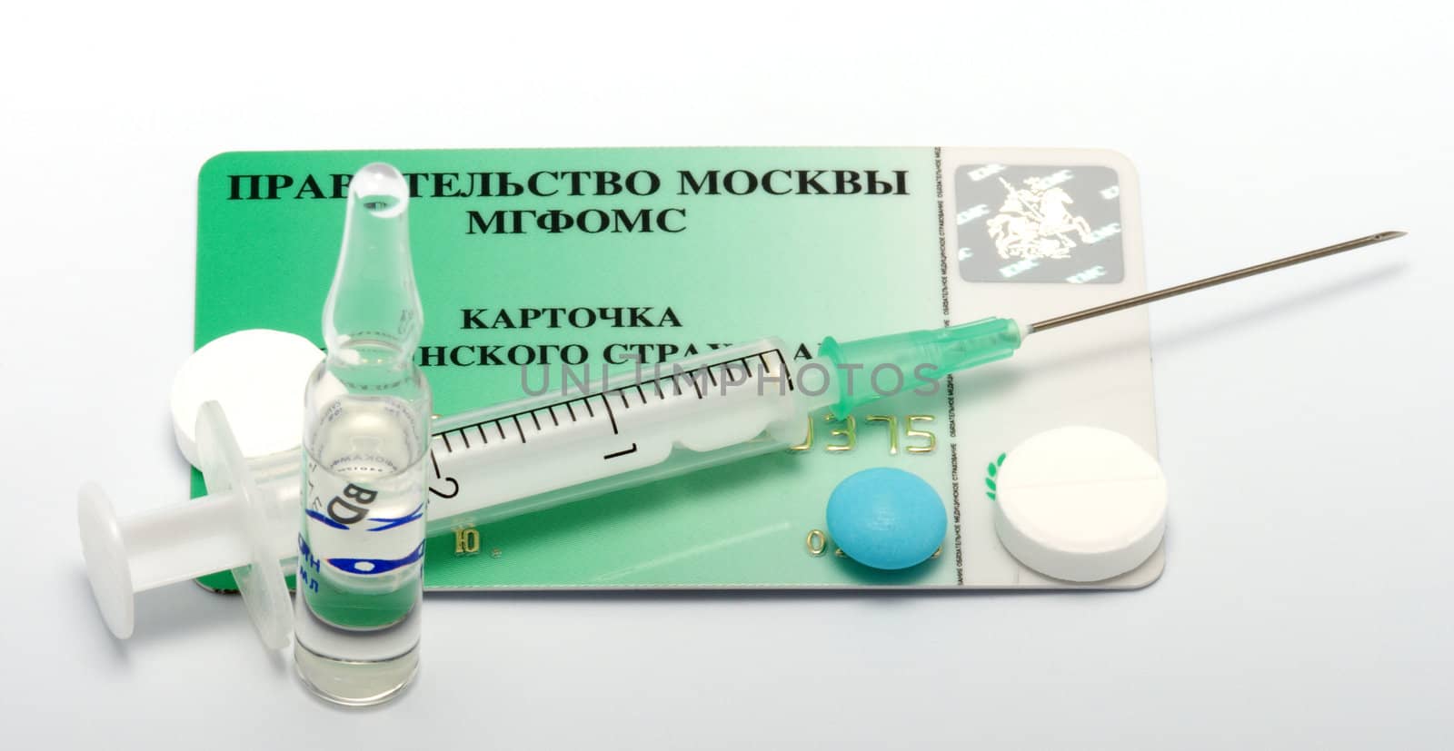 Syringe, ampoule and pills on the plastic card of obligatory medical insurance.