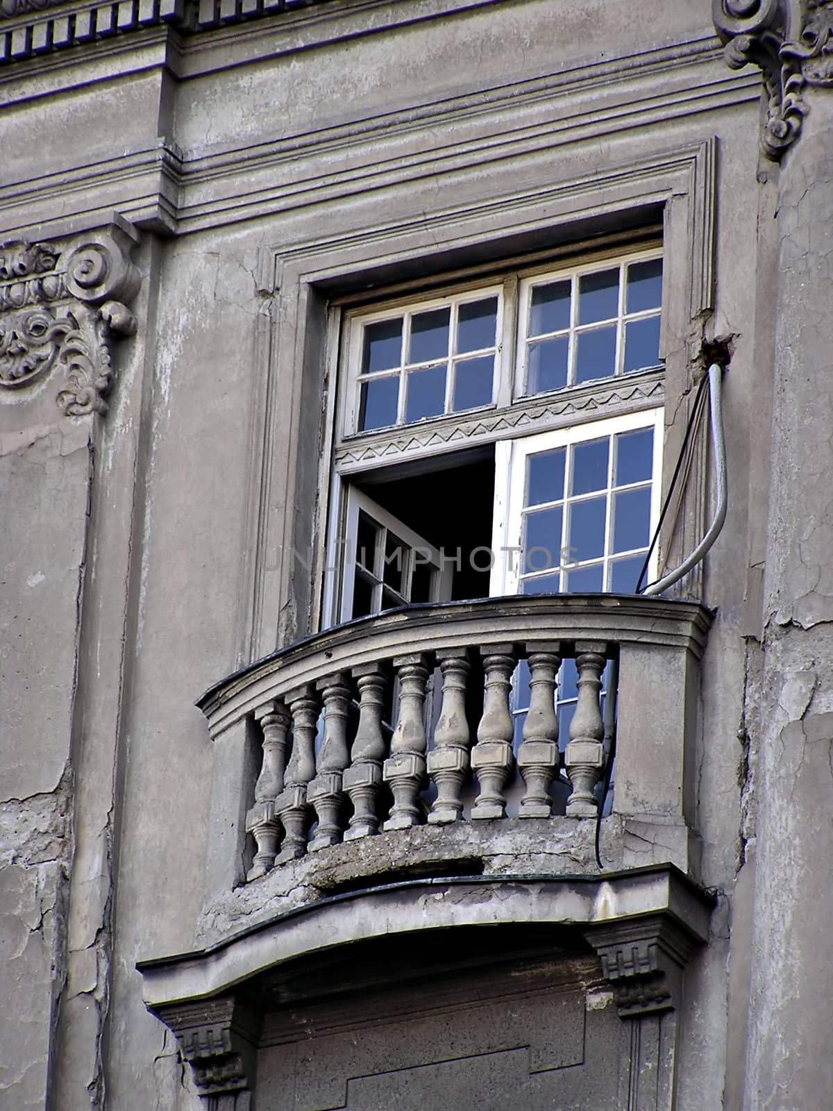 Ruined old gray builidng balcony with opened door.