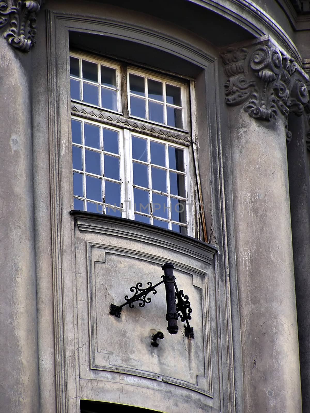 Ruined old gray building window with flag holder.