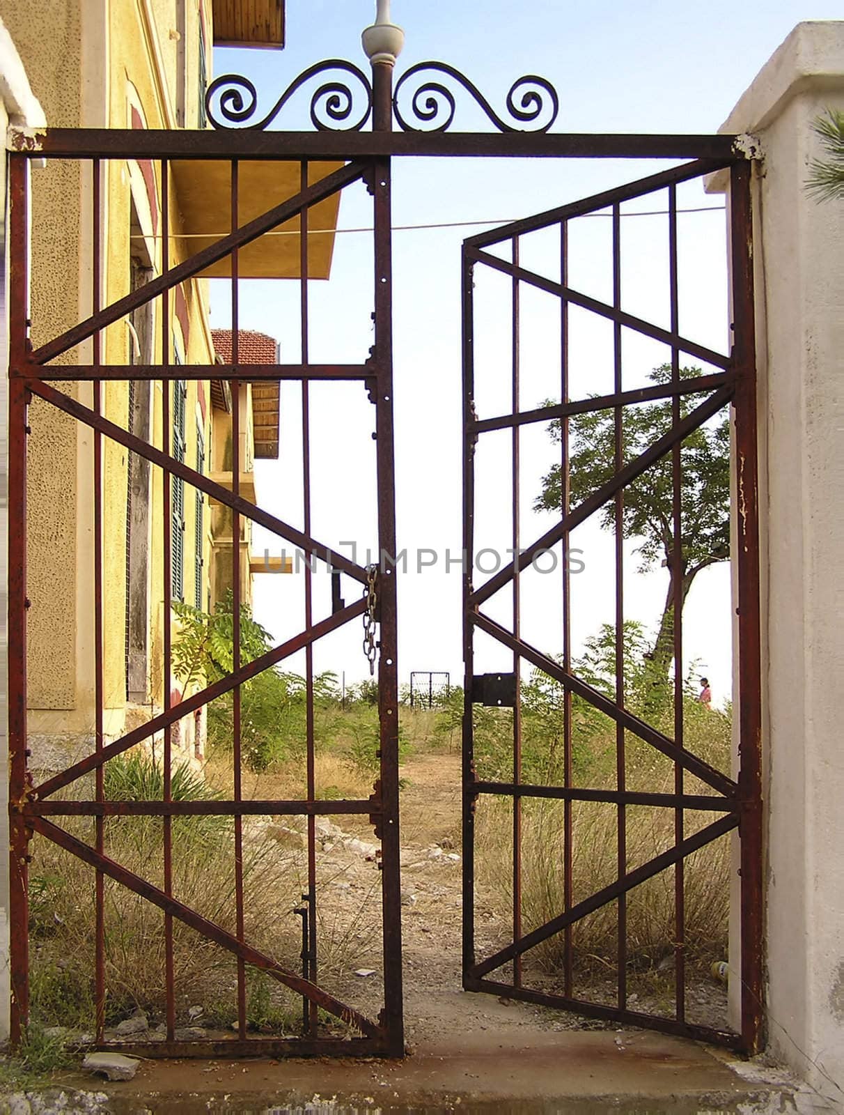 Old rusted metal gate at abandoned estate, partly opened.