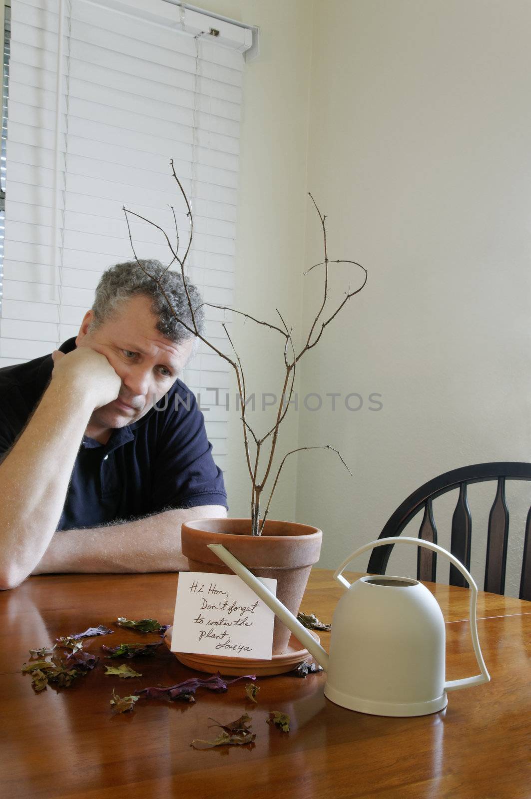 A man looking sad after realizing that he forgot to water his wife's plant.