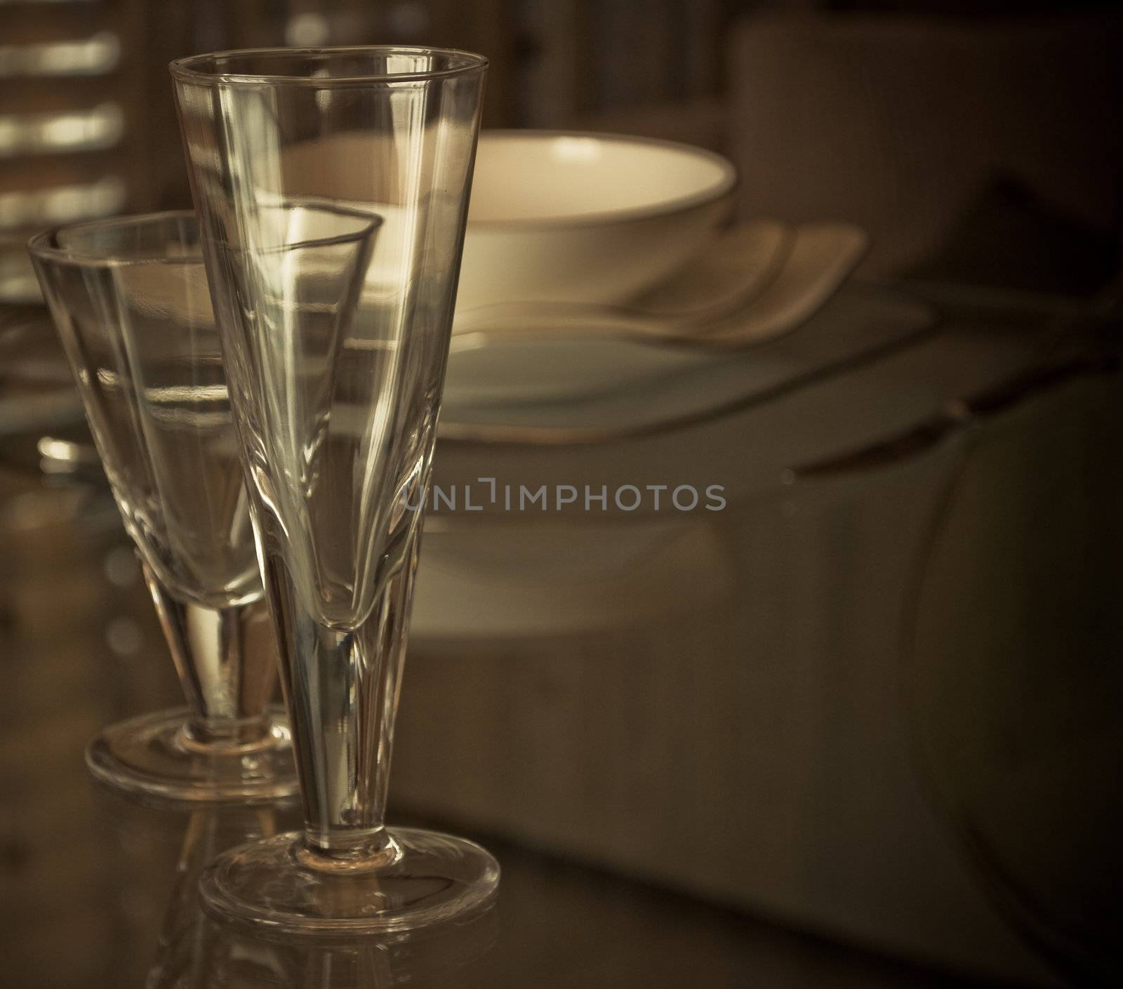 Modern glasses and plates on the glass table with light soft