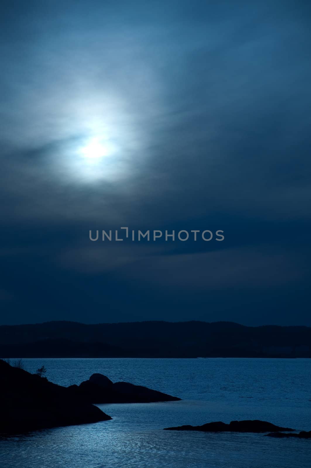 Scenic ocean view in the moonlight with hills in the background