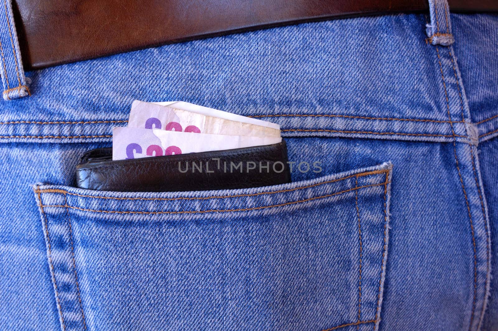 A wallet with several 20 pound bills in it pokes out of the rear pocket of someone's jeans. A temptation for a pickpocket.