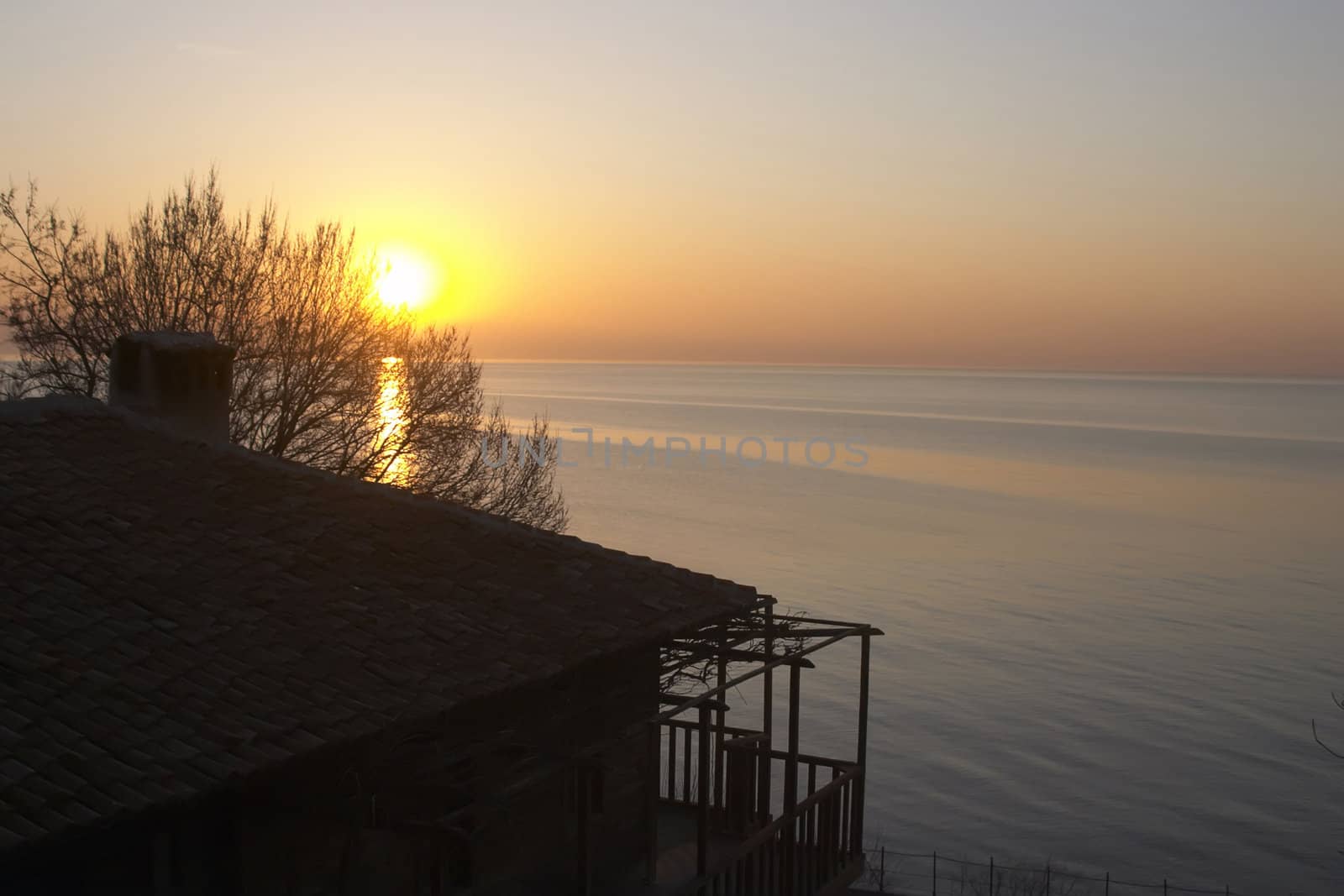 Sunset on sea background with house and tree