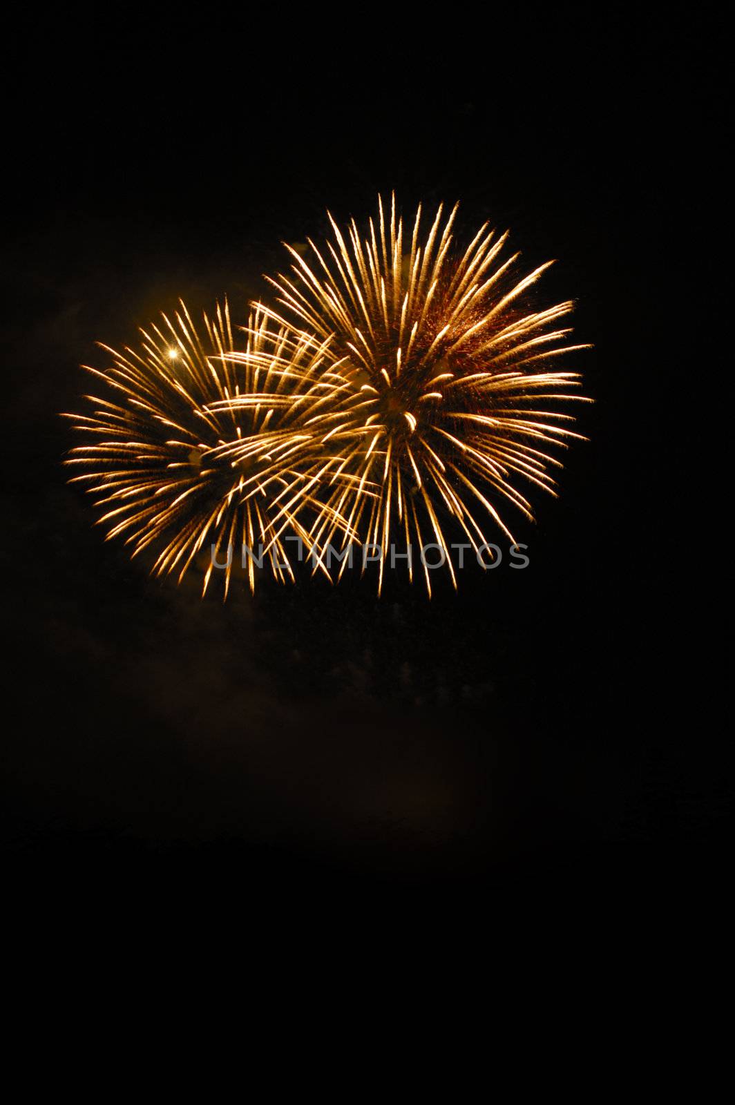 Two firework bursts isolated in the night sky. Space for text.