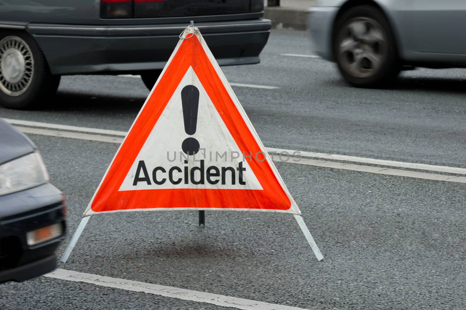 A traffic accident sign in the middle of a busy road, cars passing on either side. Motion blur on the cars.