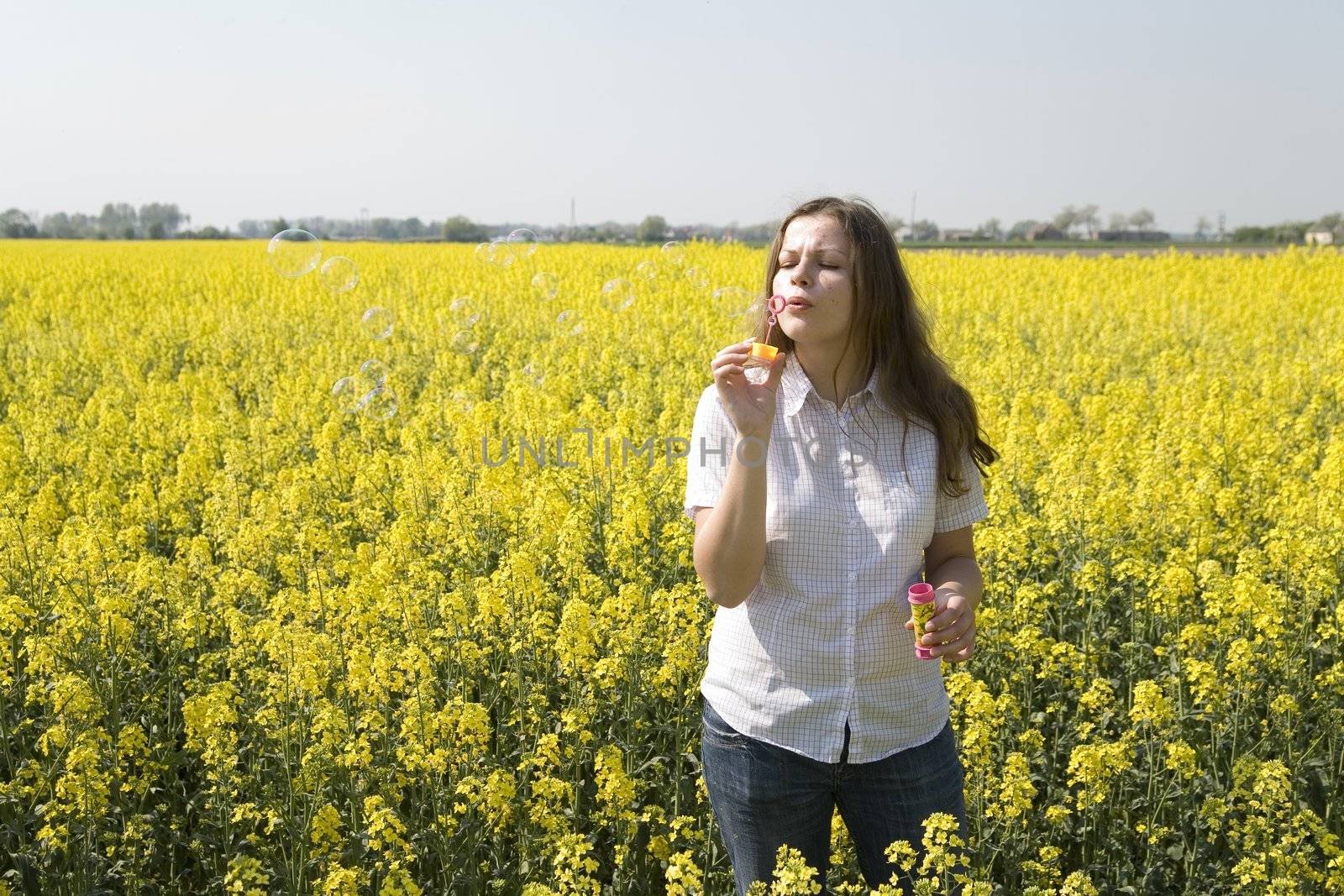 woman blowing bubbles over the rape field