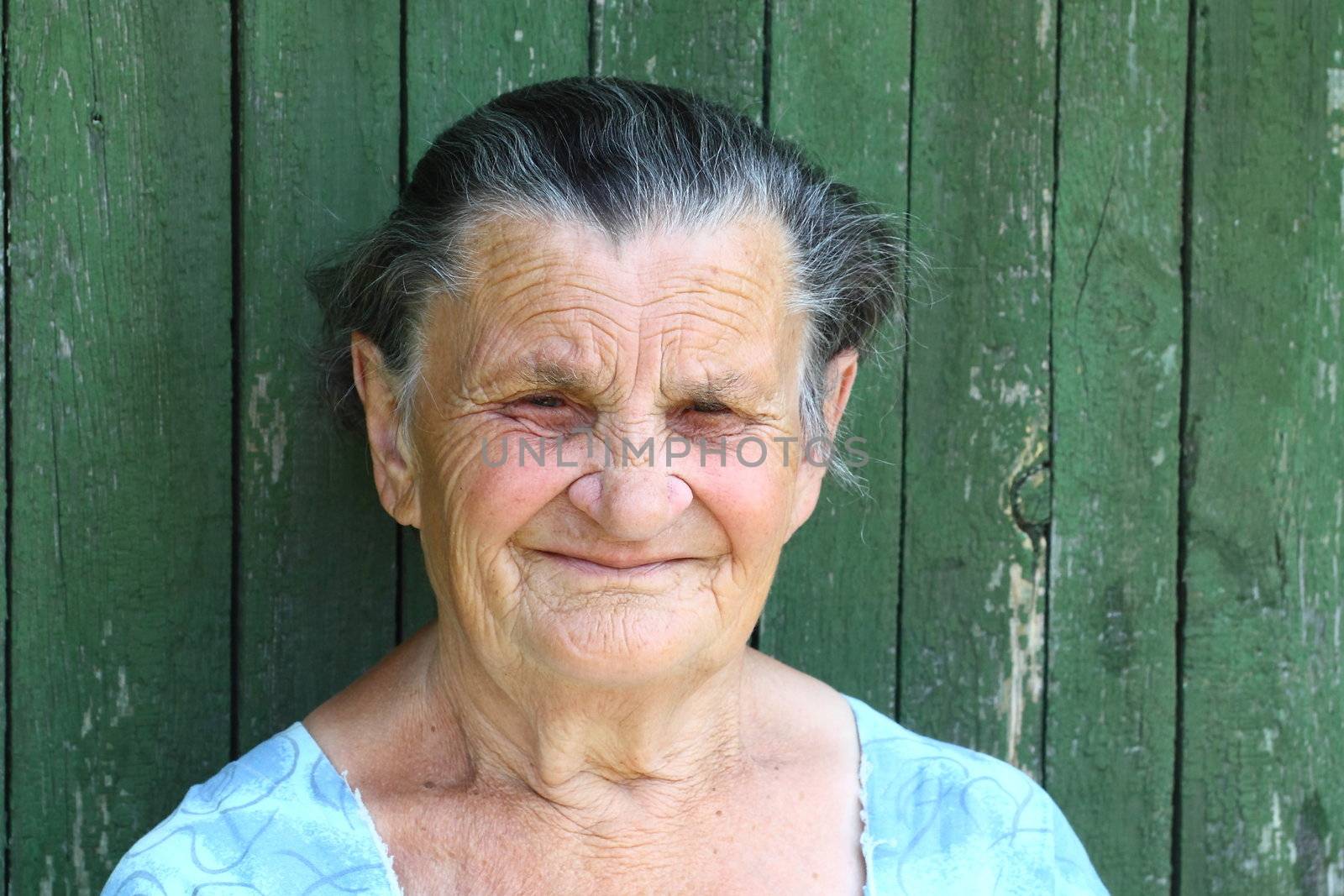 Grandma sat down on a bench near the courtyard and looks forward to the children and grandchildren to visit