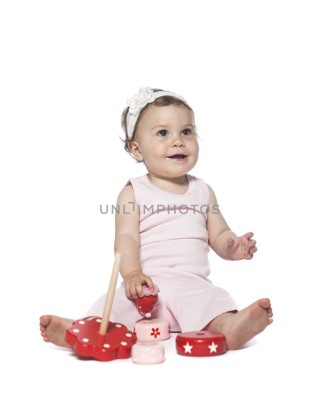 Baby in pink clothes playing with a red toy isolated on white