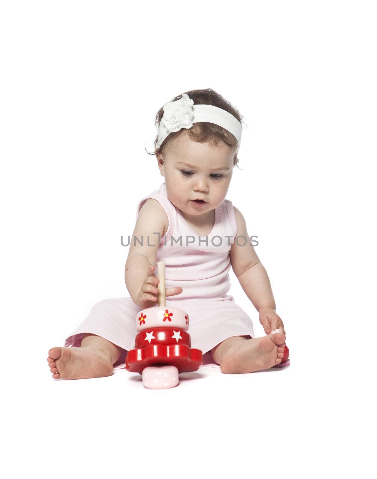 Baby in pink clothes playing with a red toy by gemenacom