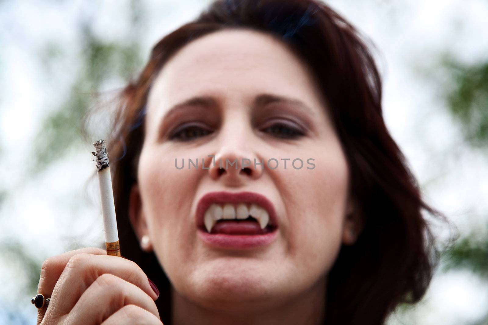 Female vampire smoking a cigarette and baring her teeth