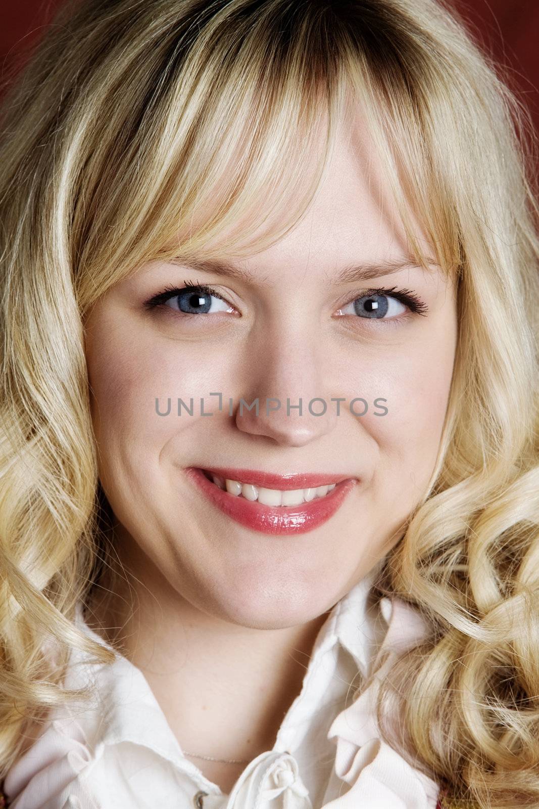 Portrait of the smiling blond girl with blue eyes close up
