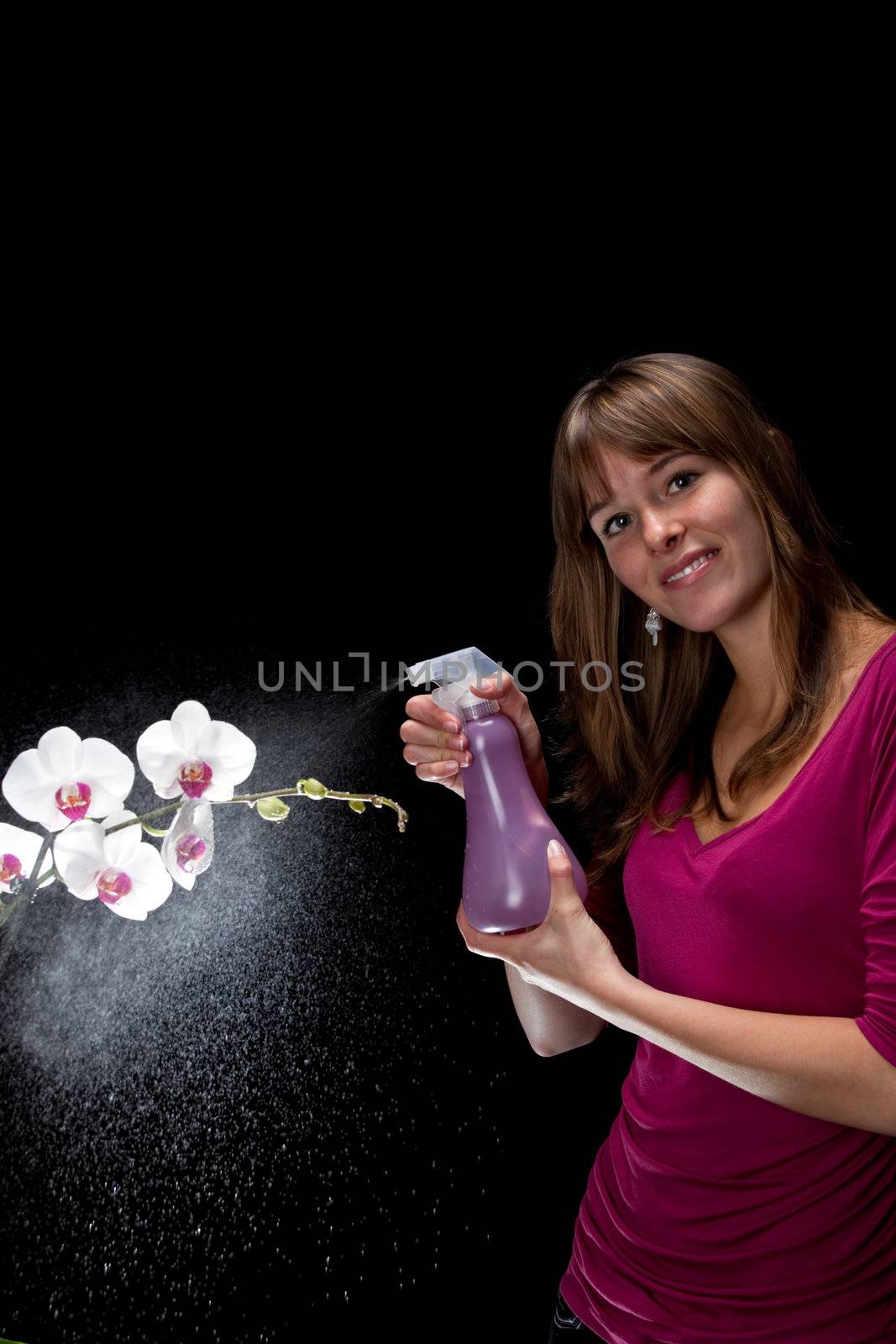 pretty young woman spraying water at an orchid