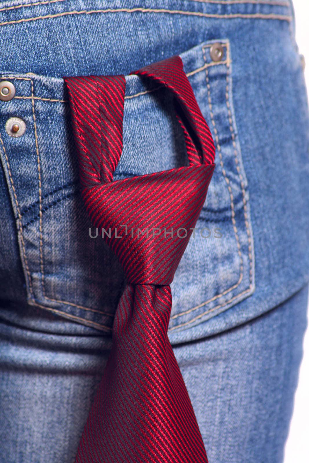 Red striped tie stuck in knot and being in a pocket female jeans removed close up