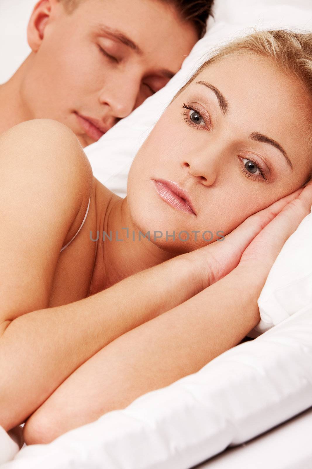 Woman suffering from insomnia while her husband is sleeping