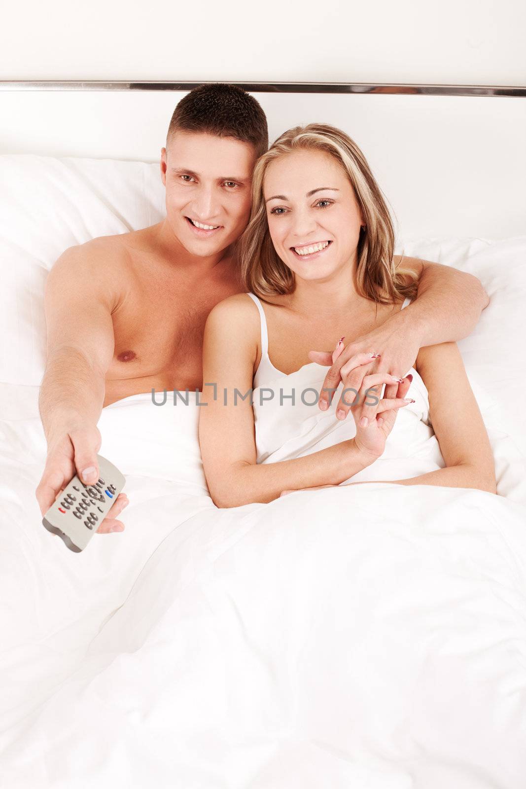Couple watching TV in bedroom by mihhailov