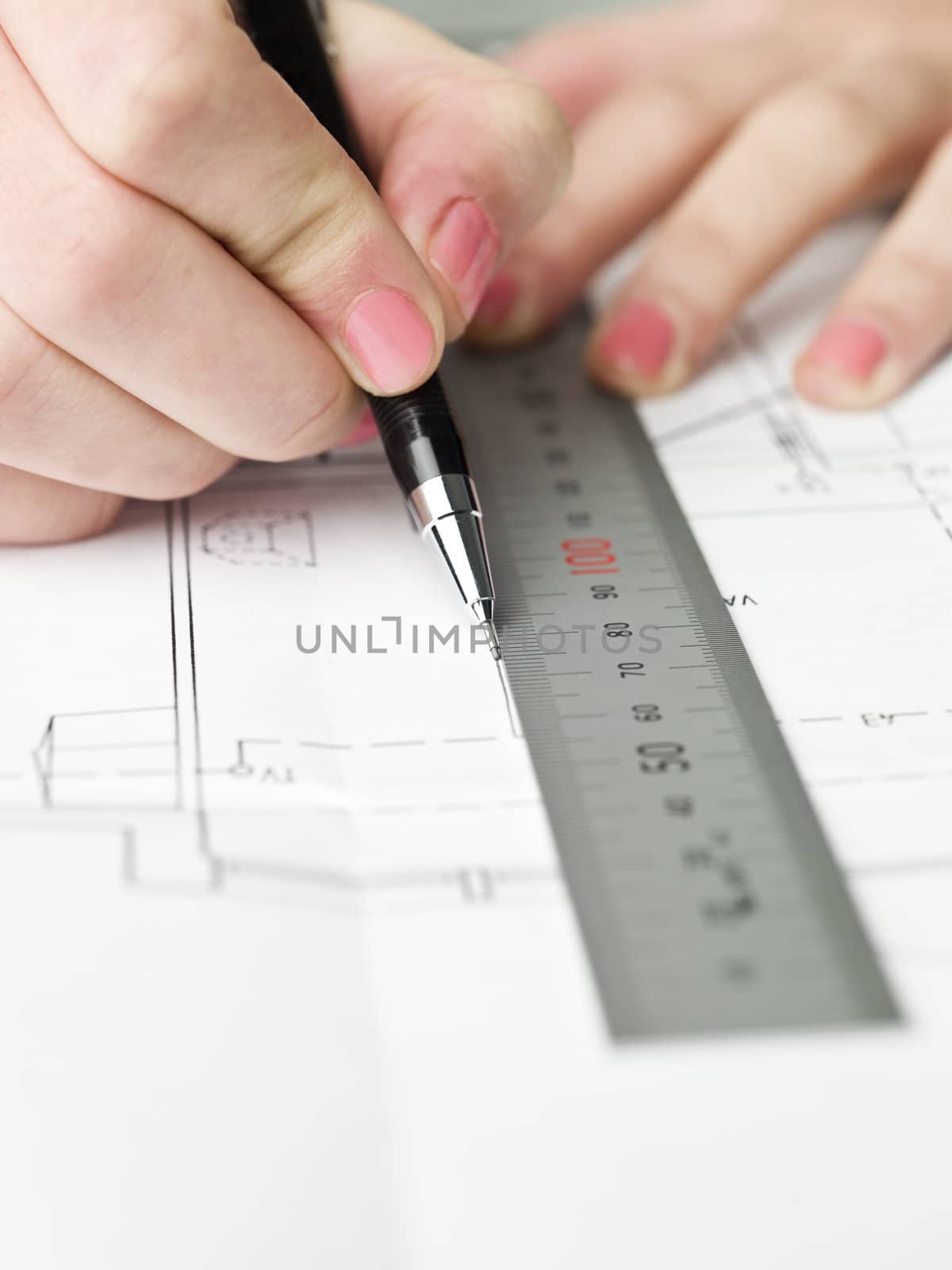 Female architect working on a bluprint, close up on hand and bluprint.