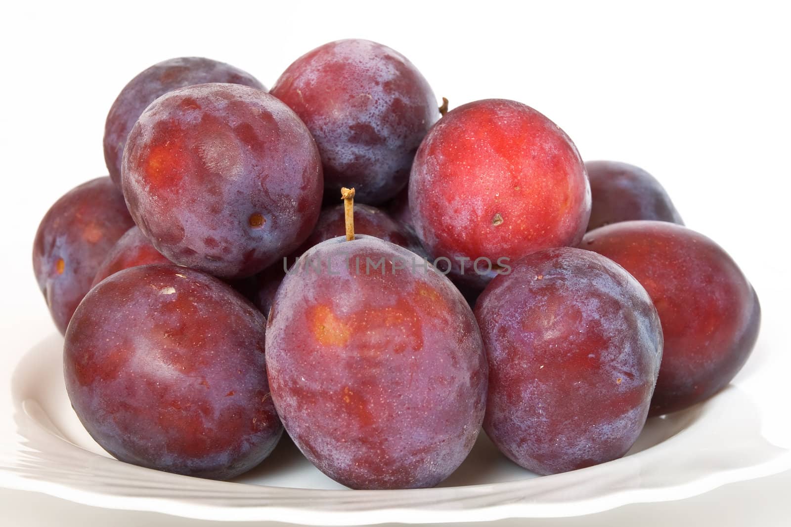 a group of red plums on a white plate