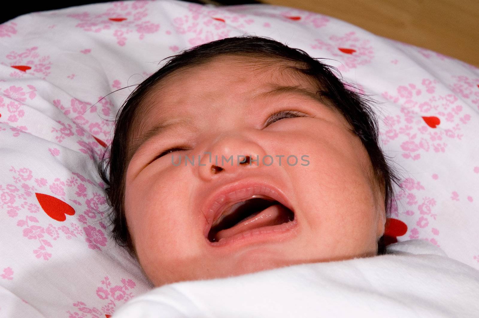 Newborn baby with eyes closed, crying