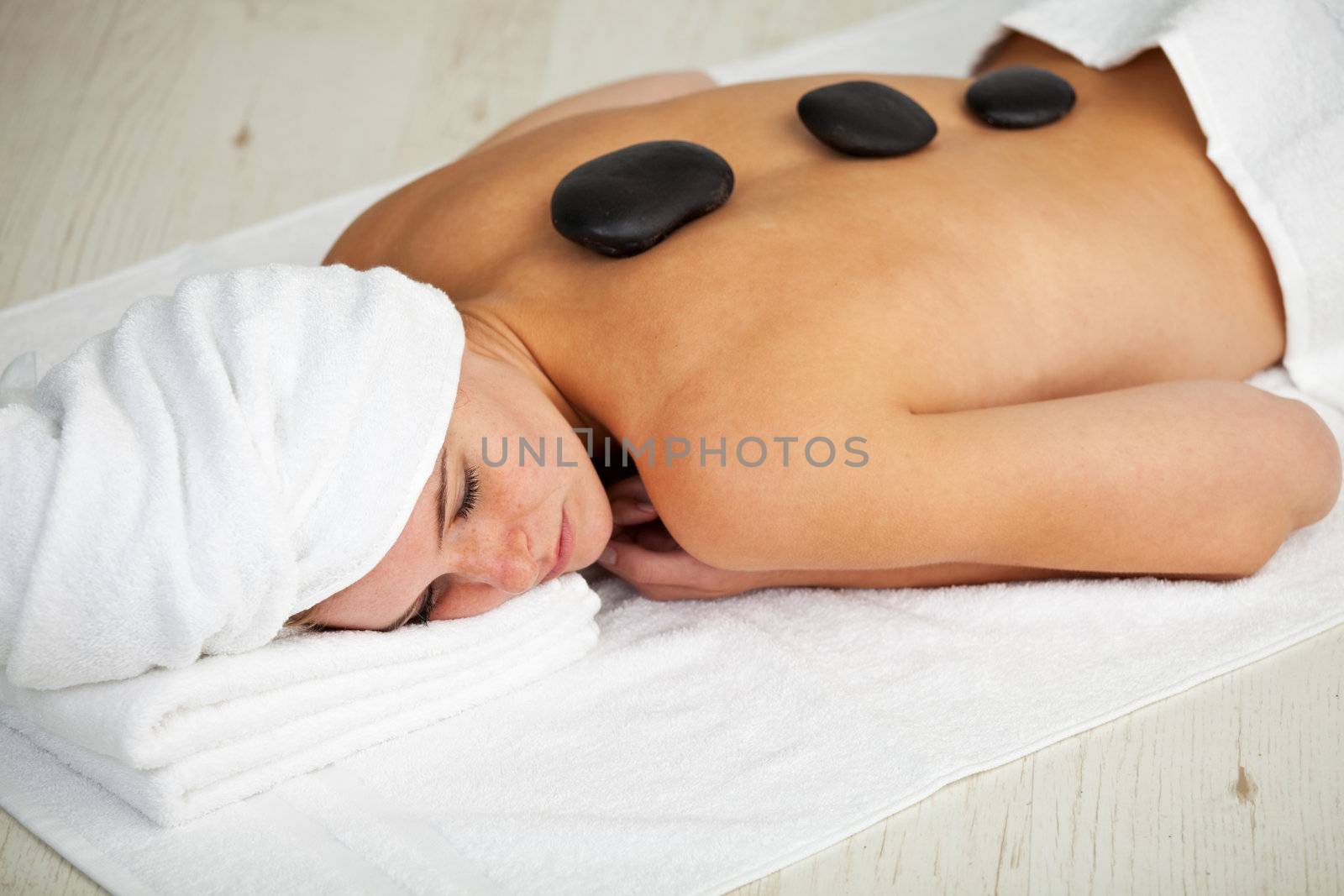 pretty young woman in a spa with stones on her back