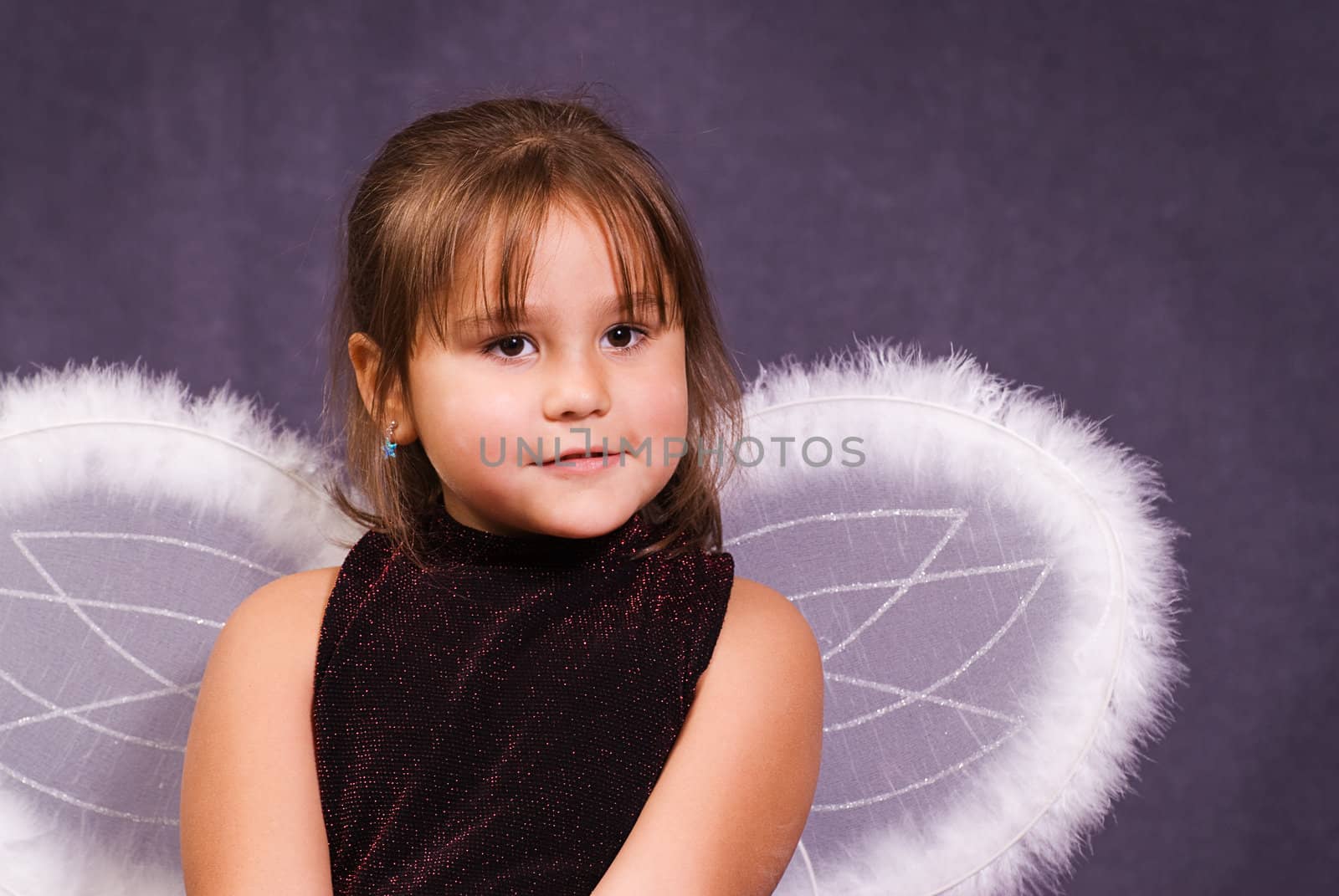 A little girl pretending to be an angel and wearing wings