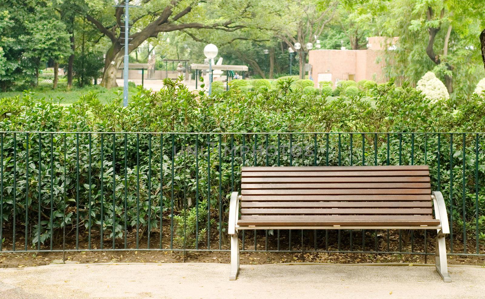 It is a brown bench with nobody in the park.