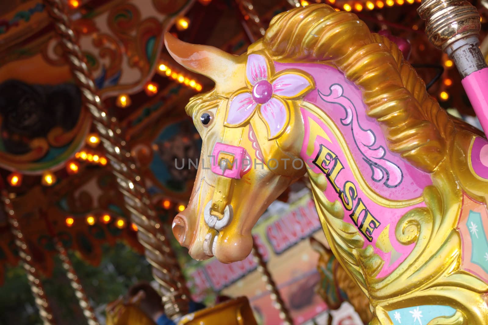 A landscape format image of the detail of a hand carved ornate horse figure on a carousel ride at a fairground.