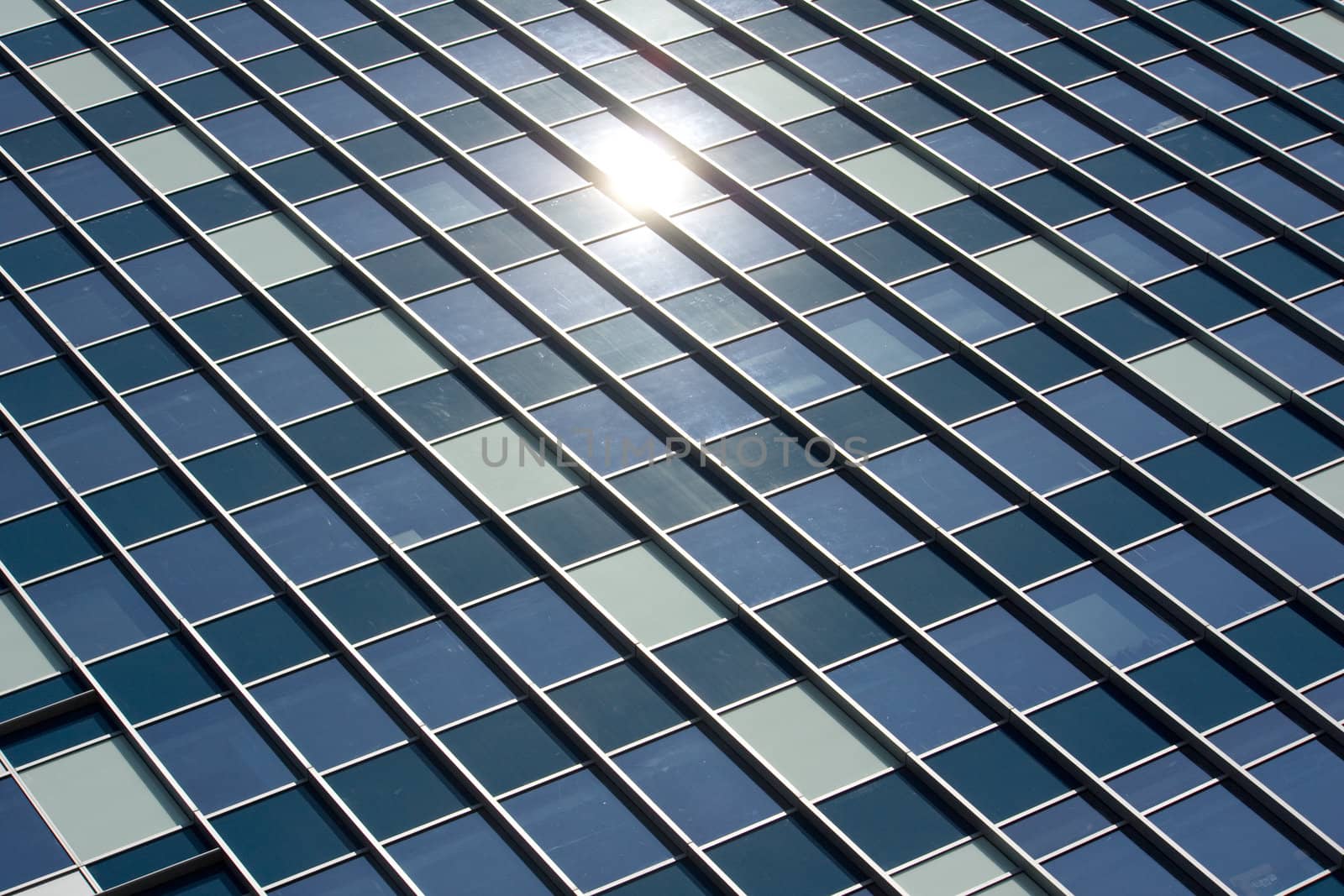 Skyscraper Glass Window Panel Office Building with reflection of the sun shining on them.