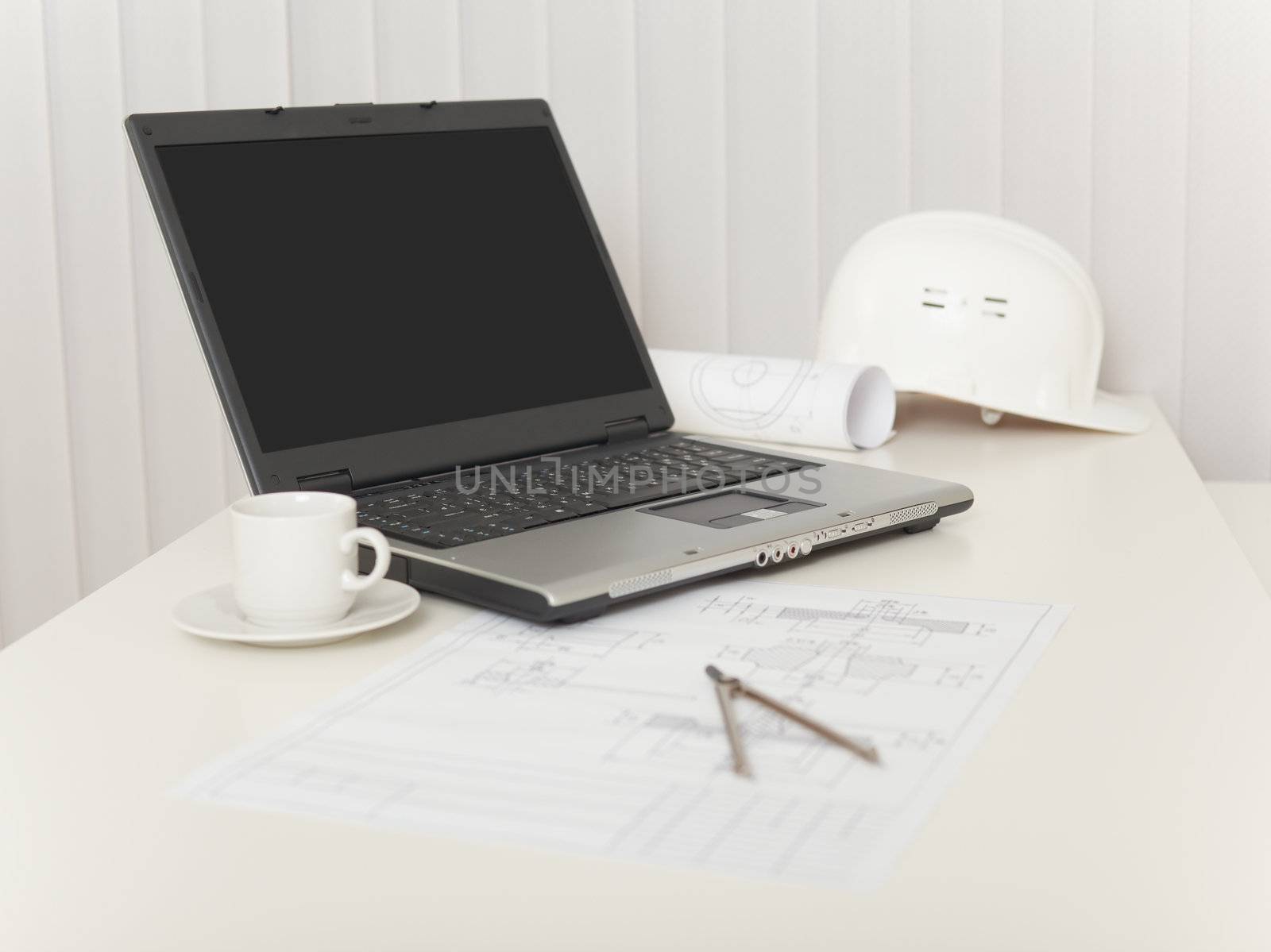 The laptop, drawings, helmet and compasses on a white table
