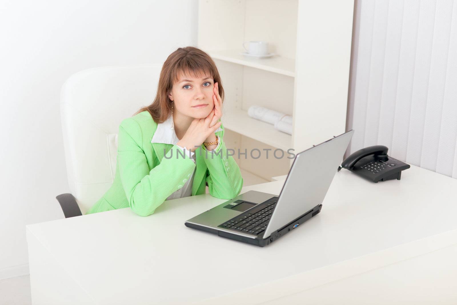 The sad girl sits at a white table at office