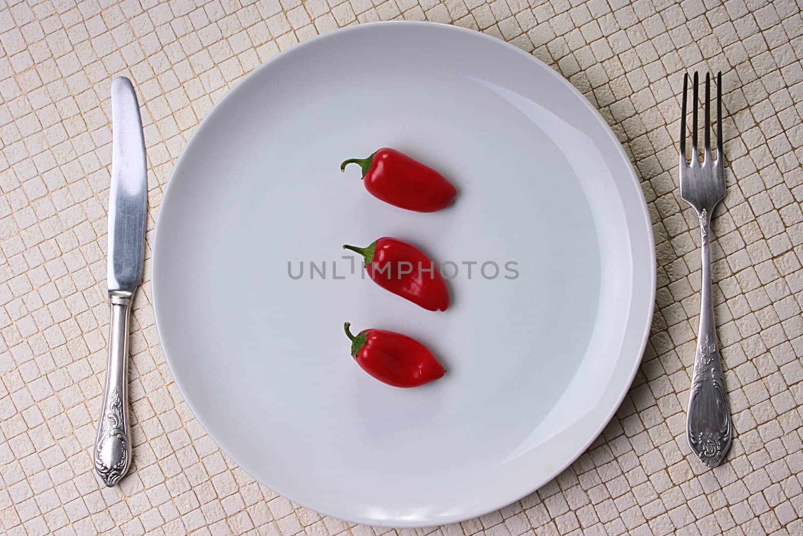 Red hot pepper on a white plate with a knife and a fork.