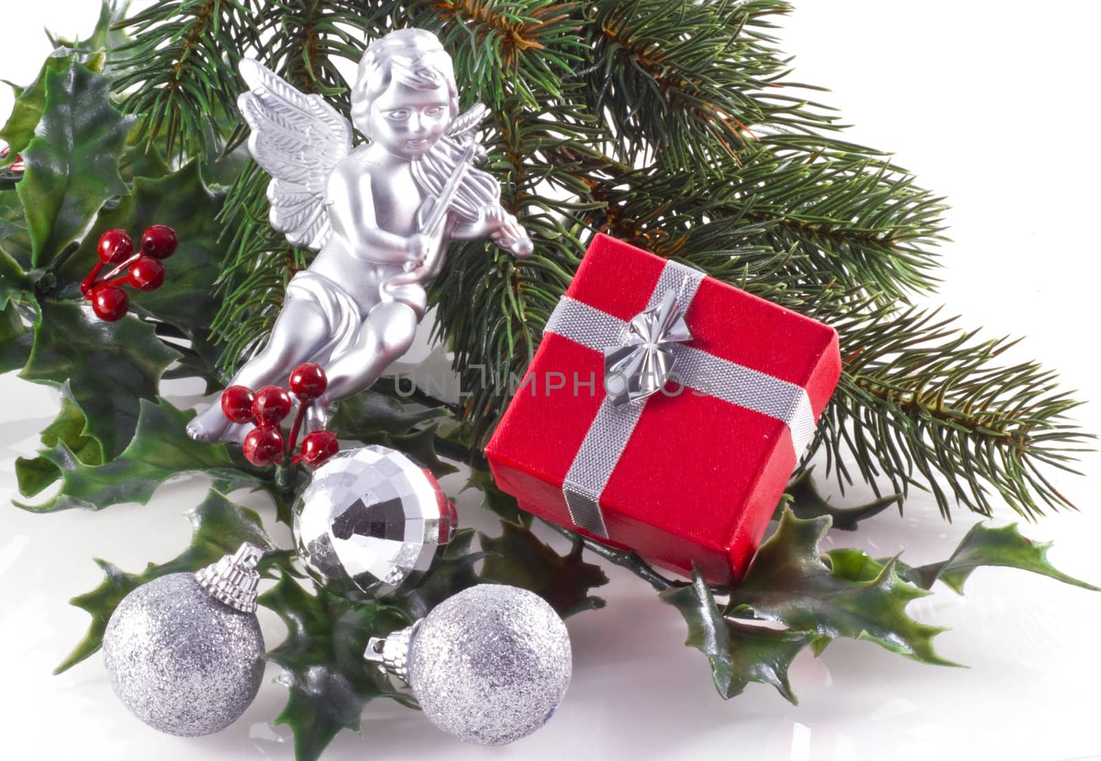 Red giftbox, silver christmas ornaments and part of a christmas tree, on a white background.