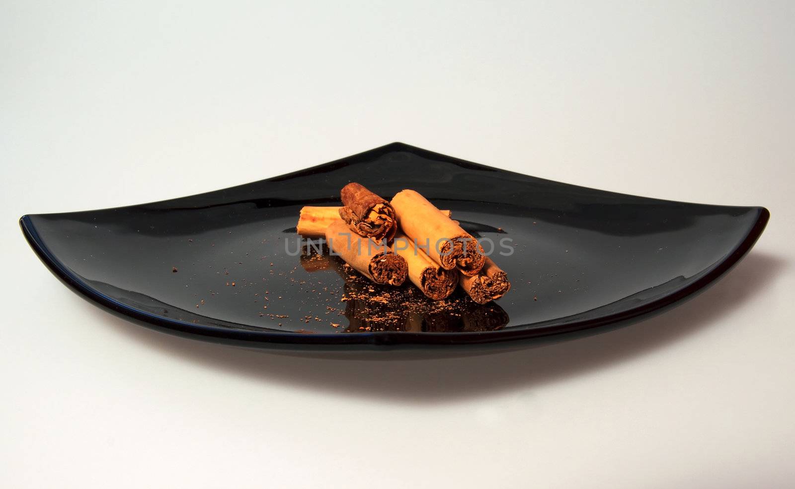 Sticks of cinnamon over a black plate, gray background