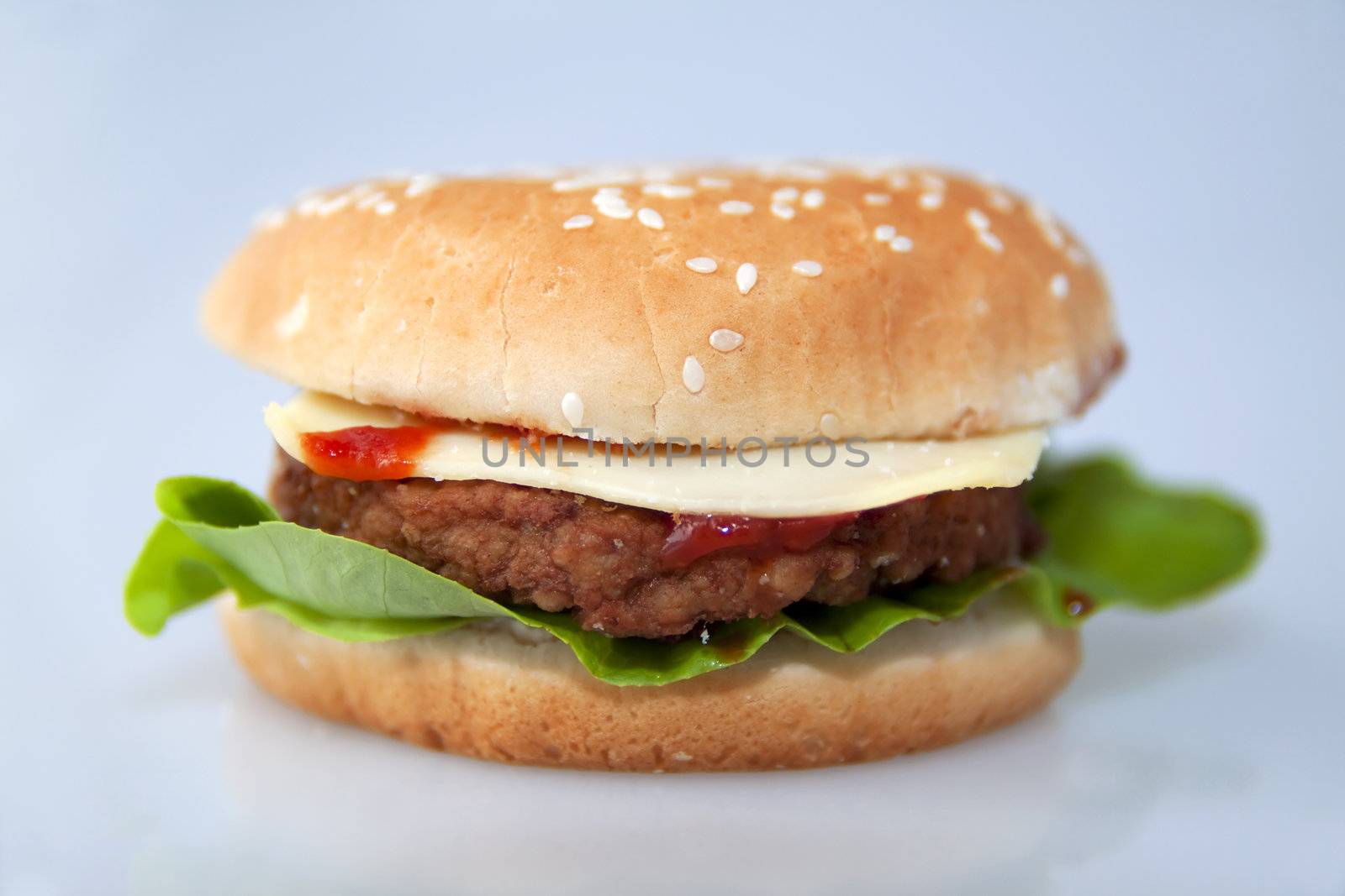 cheeseburger with salad and tomato over a gray background