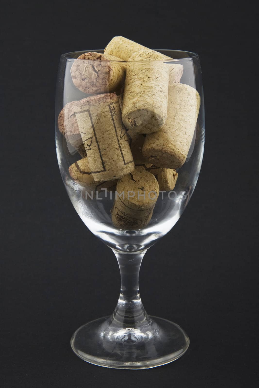 wineglass filled with corks on dark background