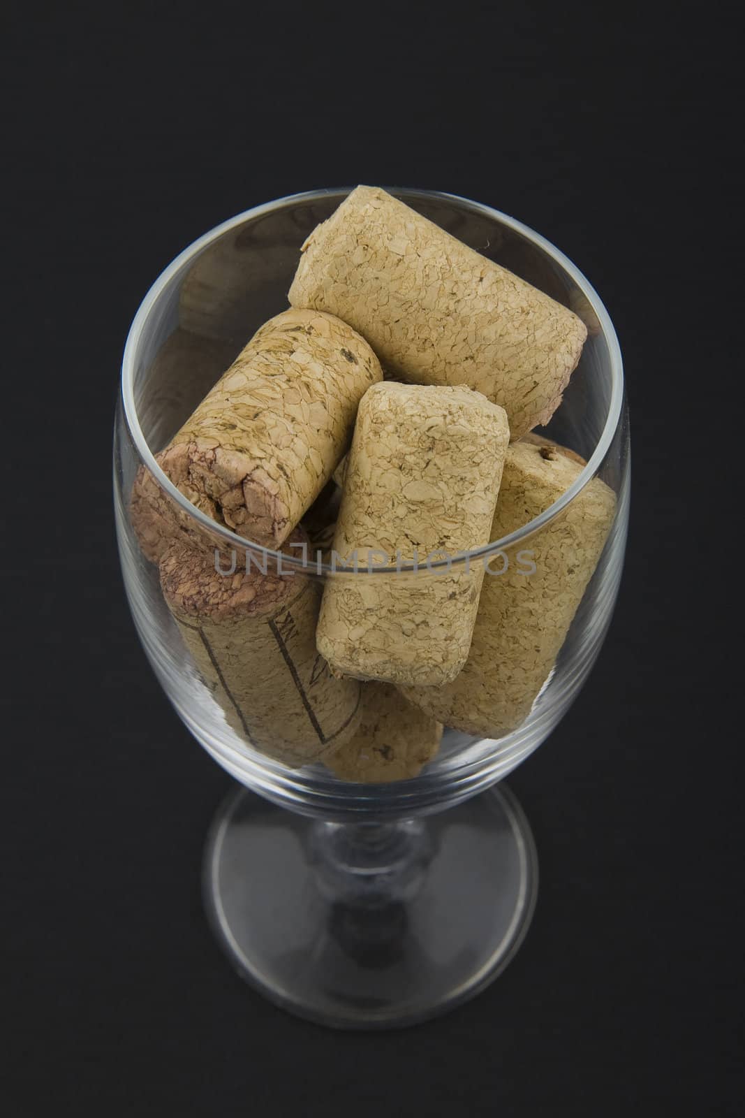 wineglass filled with corks on dark background