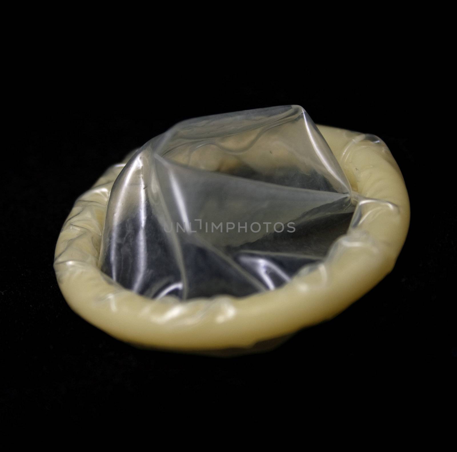 An Unused condom on black background.