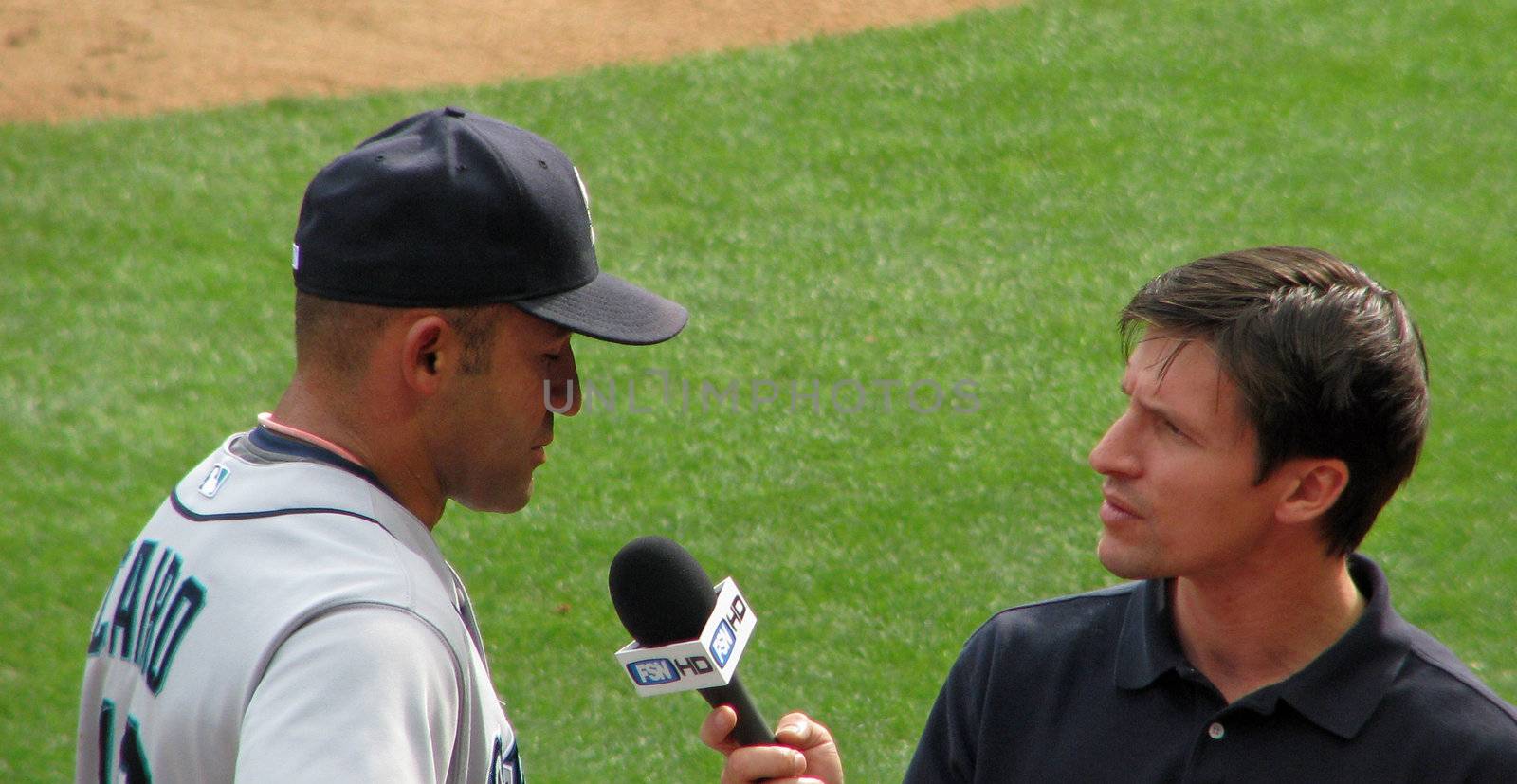 A television reporter interviews a baseball player after the game.
