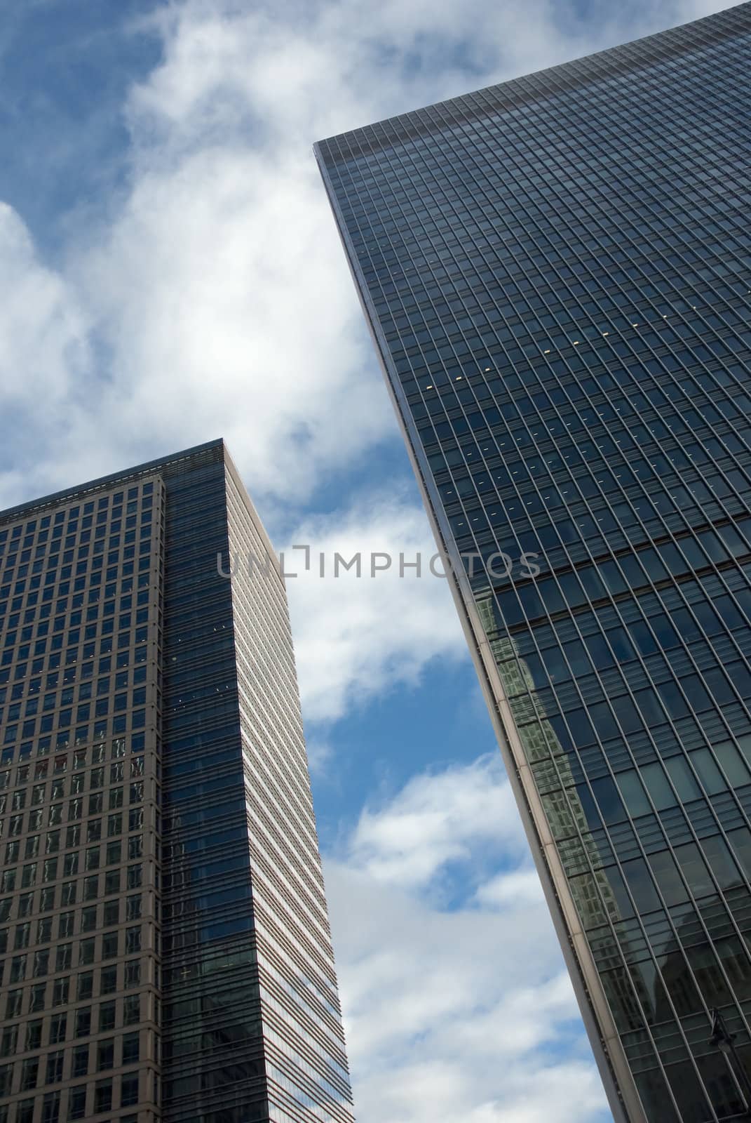 Two modern reflective buildings with clouds in the background