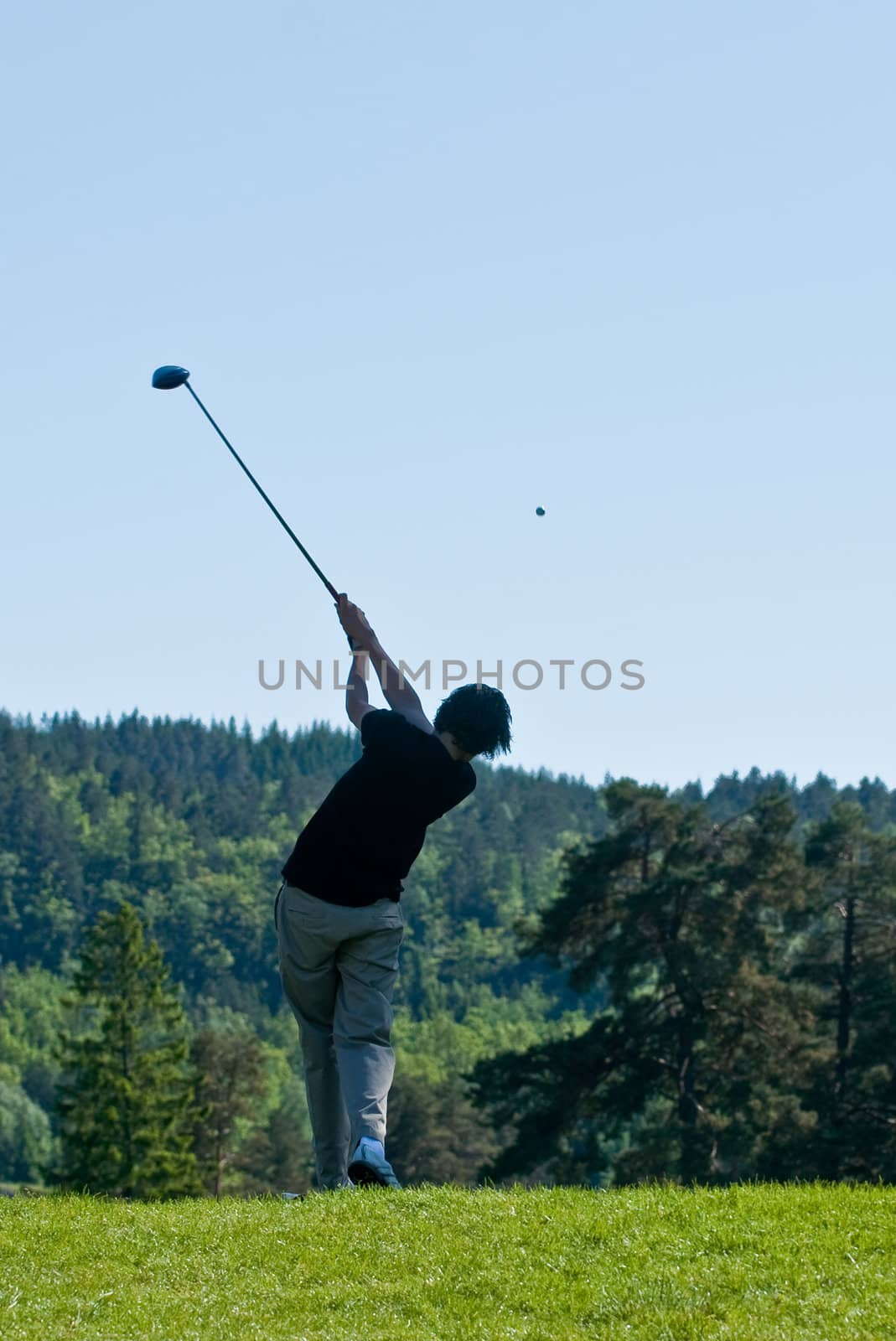 Male golfer driving in his finish with the ball in air